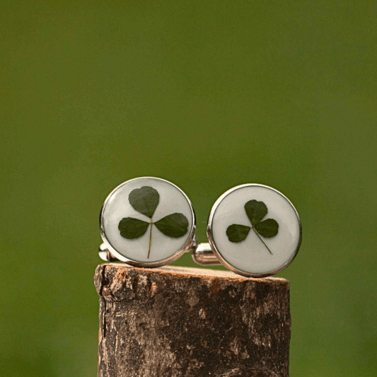 Cufflinks with a hand foraged shamrock on a wooden block against a green background