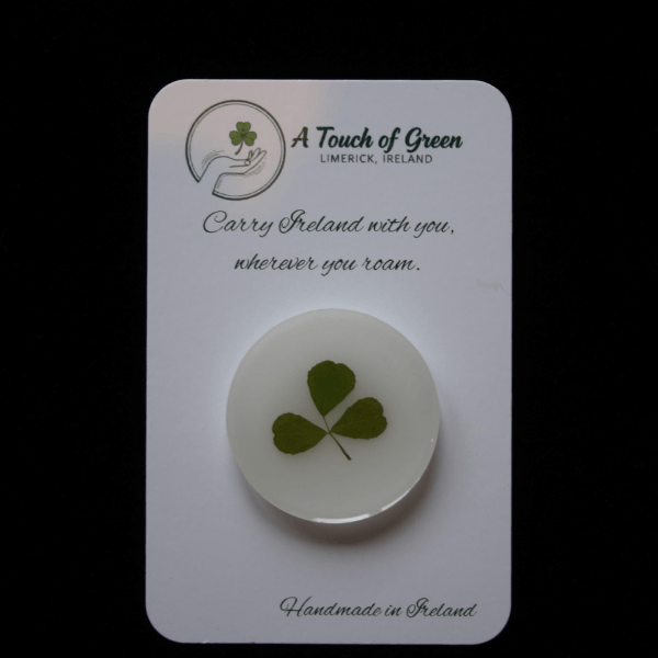 hand foraged shamrock encased in resin on a card with 'A Touch of Green' branding.