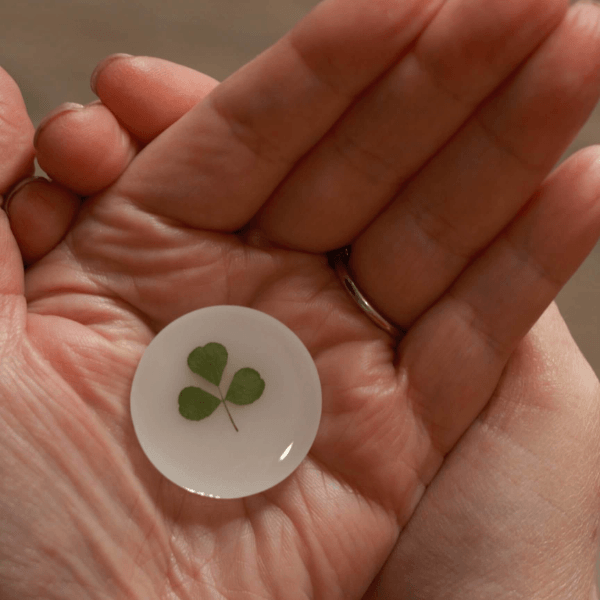 hand foraged shamrock encased in resin held in a hand